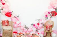 a bridal shower picnic setting with a low table, pillows, a balloon and flower heart as a party backdrop