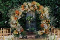 a bright round tropical wedding arch with tropical leaves, dried and spray painted ones, and fronds