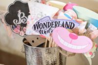 a bucket with Wonderland inspired wedding photo booth props in bold colors and arrows, smiles and more
