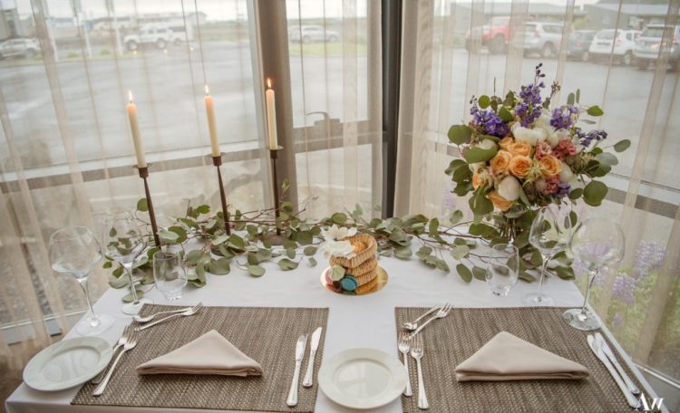 a chic Icelandic wedding reception with neutral linens greenery tall and thin candles and a tiny kransenkake with sugar blooms and macarons