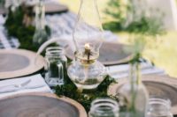 a cozy rustic or woodland tablescape with wood slices, moss, lanterns and jar mugs