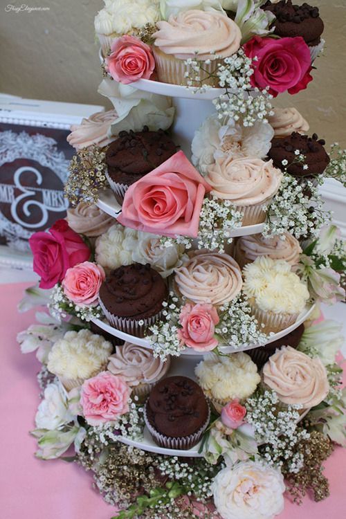 a cupcake stand with sweets and pink blooms and baby's breath is an amazing and cool idea for a party