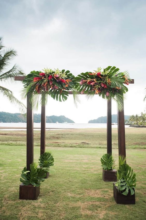 a dark floral wedding chuppah decorated with leaves and some orange and pink flowers is cool