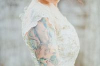 a delicate lace A-line wedding dress with an embellished bodice and cap sleeves plus a colorful ink tattoo on the arm
