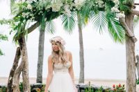 a driftwood wedding arch with cascading tropical leaves and white flowers is tropical classics