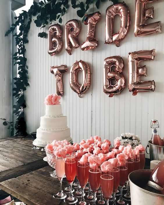 a drink station with pink champagne and cotton candy plus a wedding cake and cool letters on the backdrop