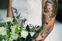 a fitting boho lace wedding dress with cap sleeves that show off tattoos on the bride’s arm and accent them