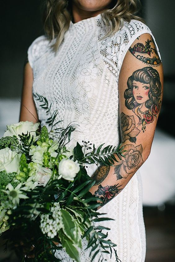 a fitting boho lace wedding dress with cap sleeves that show off tattoos on the bride's arm and accent them