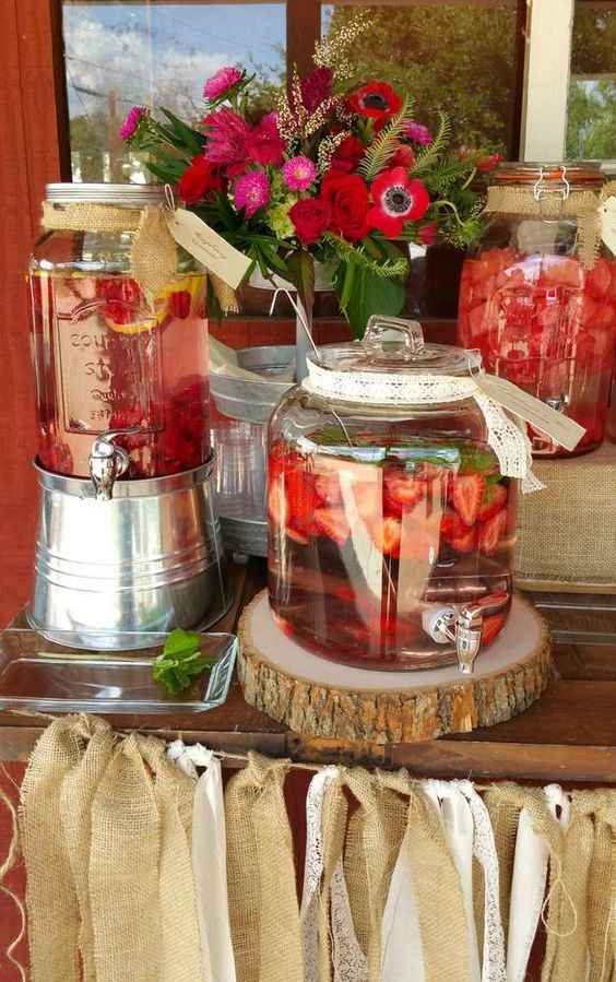 a flavored water station decorated with blooms and a burlap tassel garland for a country chic rehearsal dinner party