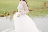a full layered tulle skirt and a sheer crop top with lace sleeves and a high neckline are a beautiful and delicate look for a modern wedding