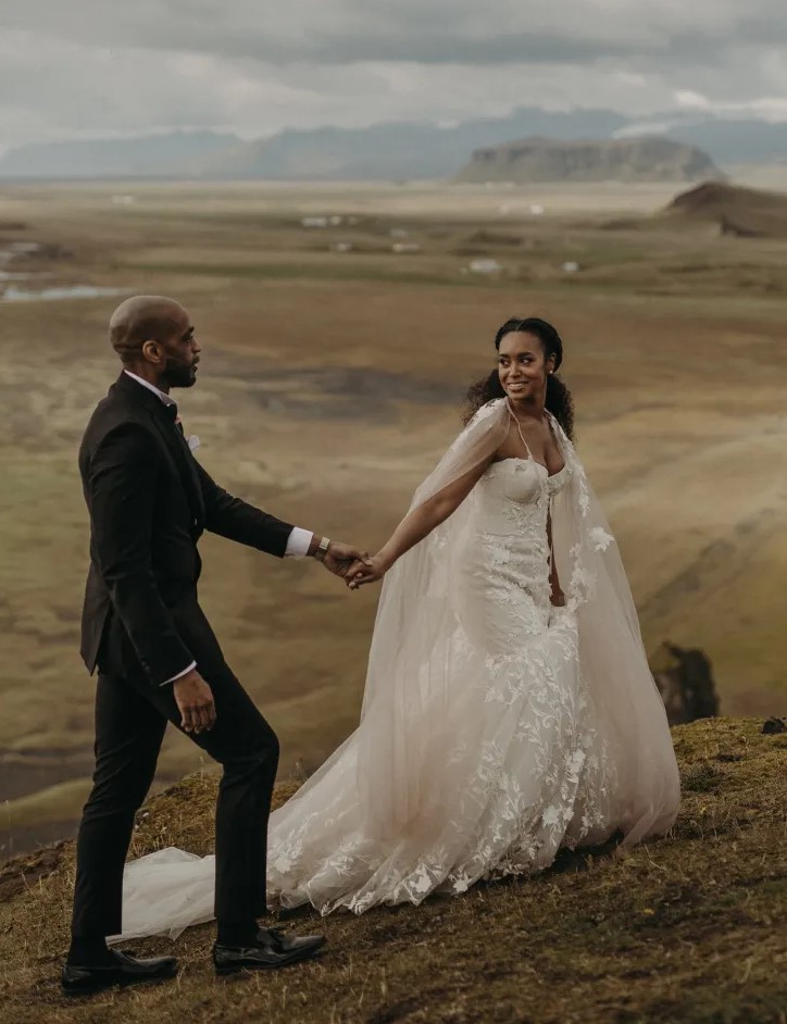 a glam Icelandic bride wearing a neutral mermaid wedding dress with lace applique, with a long train and a matching cover up