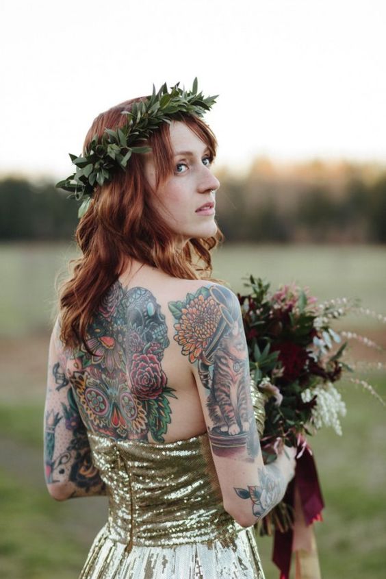 a gold sequin A-line wedding dress with an open back and no sleeves to show off the colorful bride's tattoos