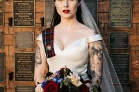 a gorgeous bridal look with an off the shoulder wedding ballgown on straps that shows off the bride’s tattoos on the arms and a plaid ribbon