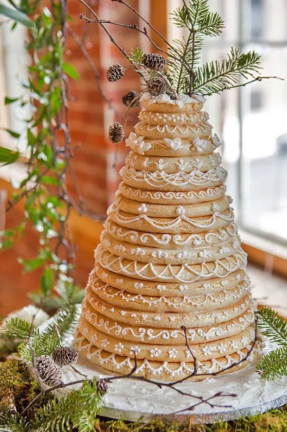 a gorgeous kransakaka topped with evergreens and pinecones and sugar patterns for a winter wedding
