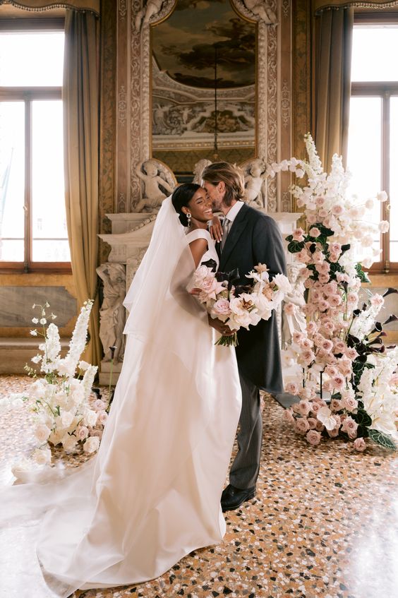 a gorgeous wedding alter of white and blush blooms and some leaves plus deep purple callas that contrast the rest of the blooms for a Venetian wedding
