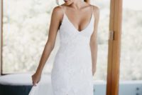 a lace sheath wedding dress with a deep neckline, spaghetti straps, a front slit and a train is very sexy
