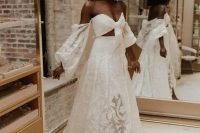 a lace two piece wedding dress with a crop top with long sleeves and a pleated maxi skirt with a train for a boho bride