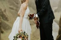 a lovely and simple A-line neutral wedding dress with a plain top and tiered skirt with a train and chic accessories, a black suit and shoes for the groom
