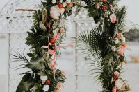 a luxurious tropical wedding arch decorated with leaves, white, orange and pink blooms is very chic