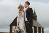 a minimalist plain mermaid wedding dress with short sleeves and a greenery crown, a black pantsuit with a white shirt and a floral tie