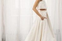 a minimalist two-piece wedding dress with a sleeveless crop top and a pleated skirt with a short train and pockets