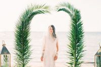 a minimalist wedding arch decorated with palm leaves is all you need to frame you two on the beach