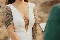 a modenr plain sheath wedding dress with a plunging neckline, no sleeves showing off the tattoos
