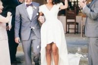 a modern plain wedding dress with a V-neckline, short sleeves, a high low skirt with a long train and silver shoes is wow
