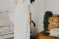 a modern plain wedding gown with a plunging neckline, long sleeves plus black mules