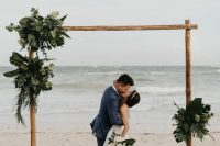 a modern tropical wedding arch decorated with greenery and tropical leaves is stylish and simple