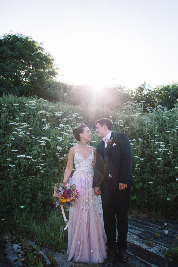 a pink A-line floral wedding dress with floral appliques and embellishments, with a V-neckline and spaghetti straps