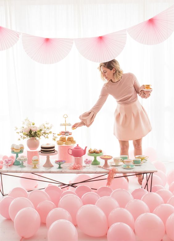a pink bridal shower tea party with balloons, paper fans and a large dessert table