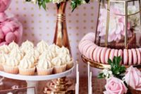 a pink dessert table with cake pops, cupcakes, cookies and lots of blooms in ivory and pink