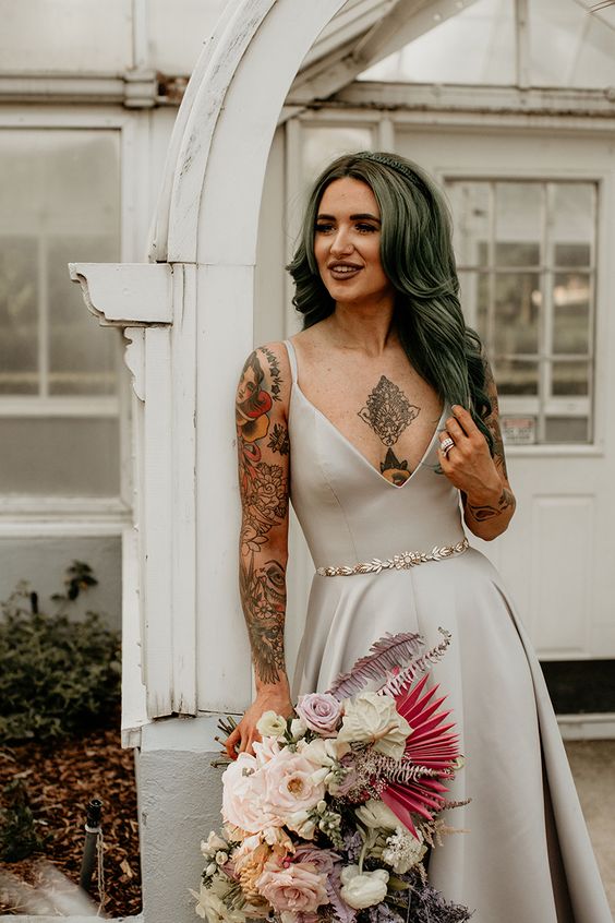 a plain A-line wedding dress with a deep V-neckline and tattoos on the chest and arm that are shown off in a beautiful way