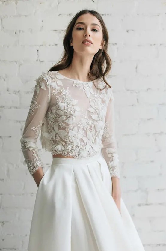 a plain ivory skirt with pleats and a floral applique crop top with sleeves are a very sophisticated and chic ensemble for a wedding