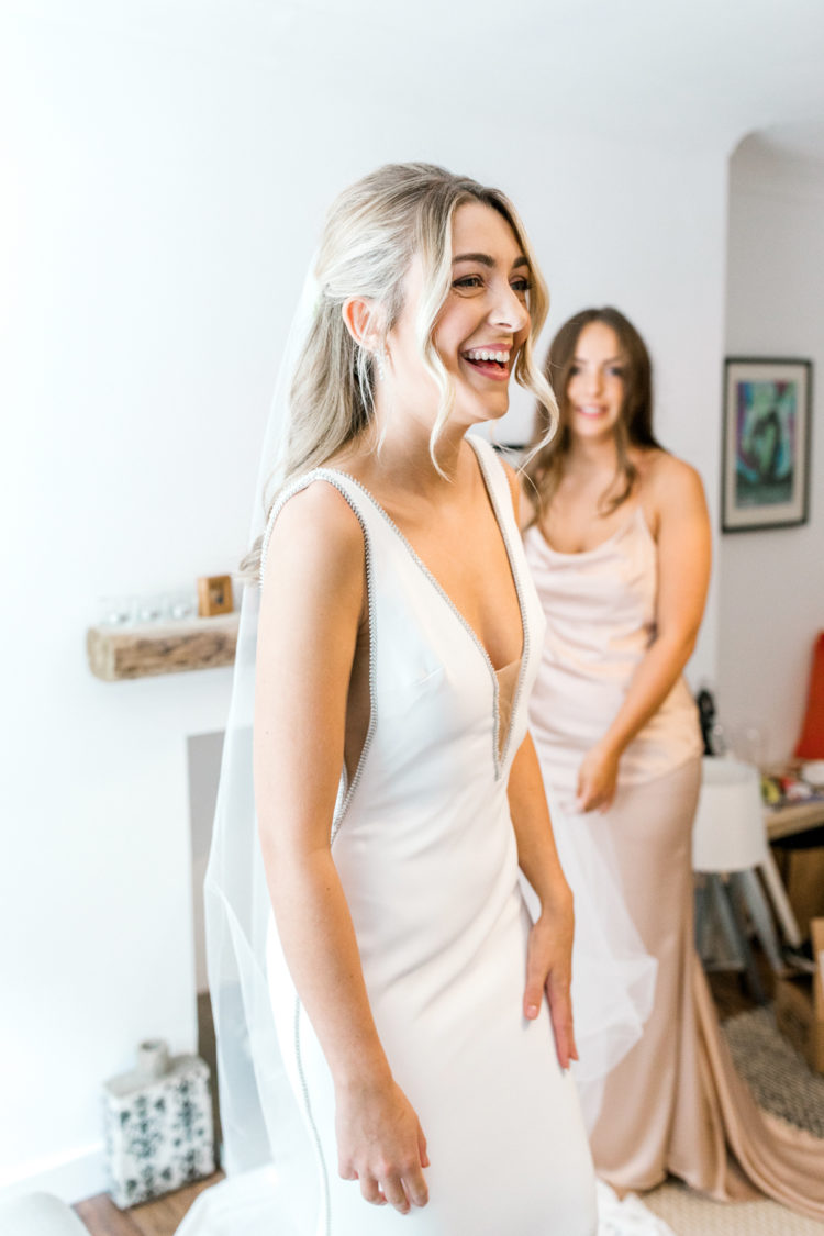 a plain sheath wedding dress with a covered plunging neckline and cutout sides plus beading along the edges