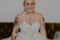 a pretty strapless wedding ballgown with a belt showing off bride’s tattoos on the shoulders and arms plus on the chest