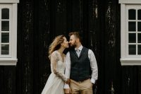 a pretty wedding dress with a lace bodice and long sleeves and pleated skirts, groom wearing tan pants, a white shirt, a grey checked waistcoat and brown shoes