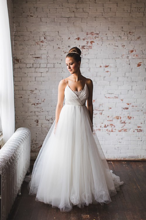 a refined A-line wedding dress with a draped bodice, a lace neckline, a layered tulle skirt for a chic bridal look