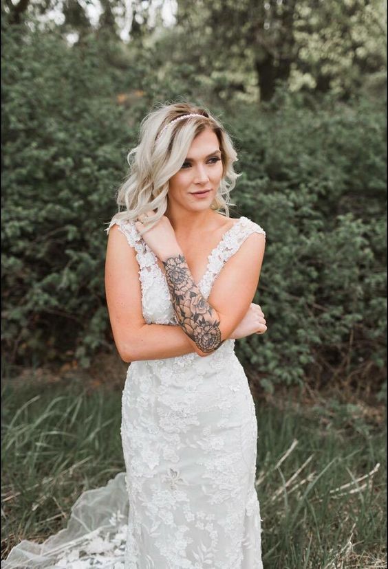 a romantic bridal look with a lace fitting wedding dress with a train and thick straps to show off the bride's tattoo on the arm