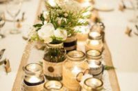 a rustic table centerpiece with jars with candles and neutral floral and greenery arrangements