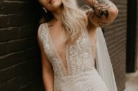 a sheath lace wedding dress with no sleeves and a plunging neckline plus tattoos that are shown off