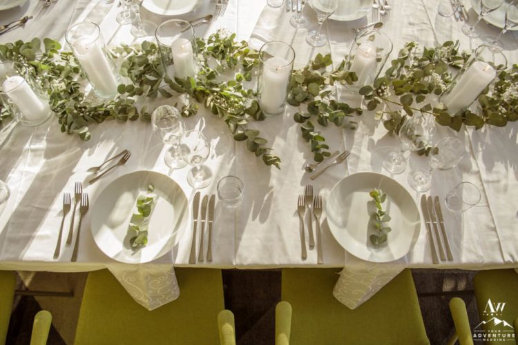 a stylish and simple Icelandic wedding tablescape with neutral linens, greenery and pillar candles on the table and elegant cutlery