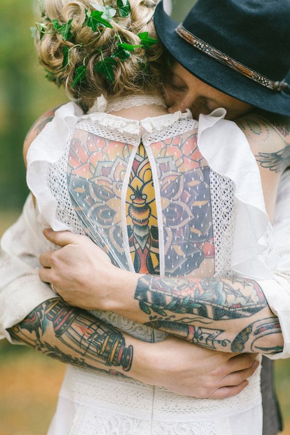 a vintage boho wedding dress witha semi sheer and cutout back that shows off the colorful bride's tattoo