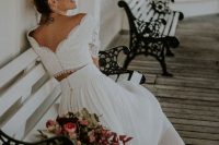 a vintage bridal ensemble with an off the shoulder lace crop top and a pleated midi skirt, silver shoes and a floral accent in the hair