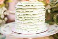 a vintage-inspired bridal shower cake in mint green with ruffles and a fresh bloom on top