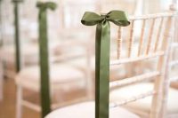 a white chair accented with a green silk bow and nothing else for a chic and tasteful wedding aisle look