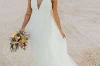an A-line plain wedding dress with a plunging neckline, thick straps and a layered skirt plus statement earrings