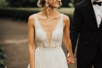 an A-line wedding dress with a lace bodice, a plunging neckline and a layered skirt with lace appliques
