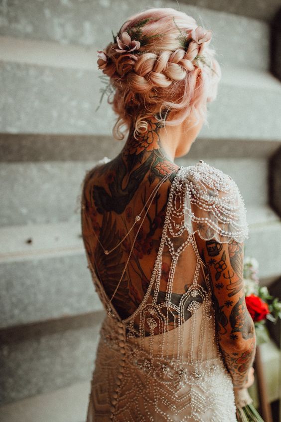 an embellished wedding dress with cap sleeves and a cutout back that show off the bride's tattoos on the back, arms and neck